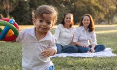 A joyful family enjoying a picnic in the park with a playful toddler in the foreground.